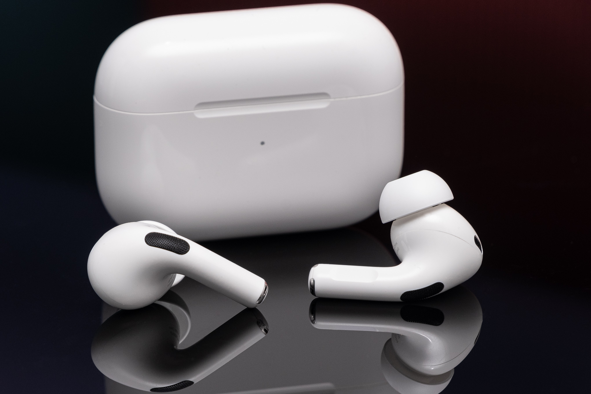 تم تصوير AirPods من الجيل الثاني من Apple على سطح أسود عاكس.