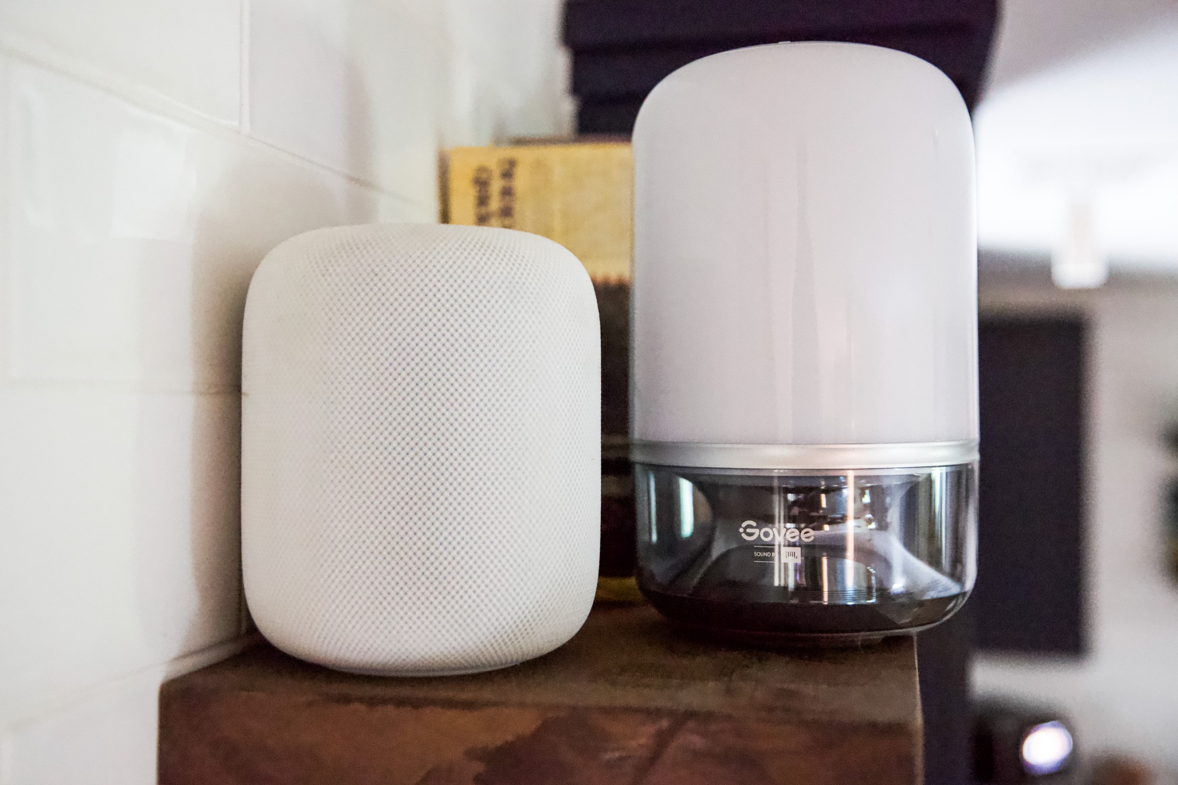 مصباح طاولة Govee هو حجم وشكل مماثل لمكبر الصوت الذكي HomePod من Apple (يسار) ، ولكنه يحتوي على شبكة مكبر صوت أصغر وجسمها الرئيسي هو مصباح بلاستيكي.