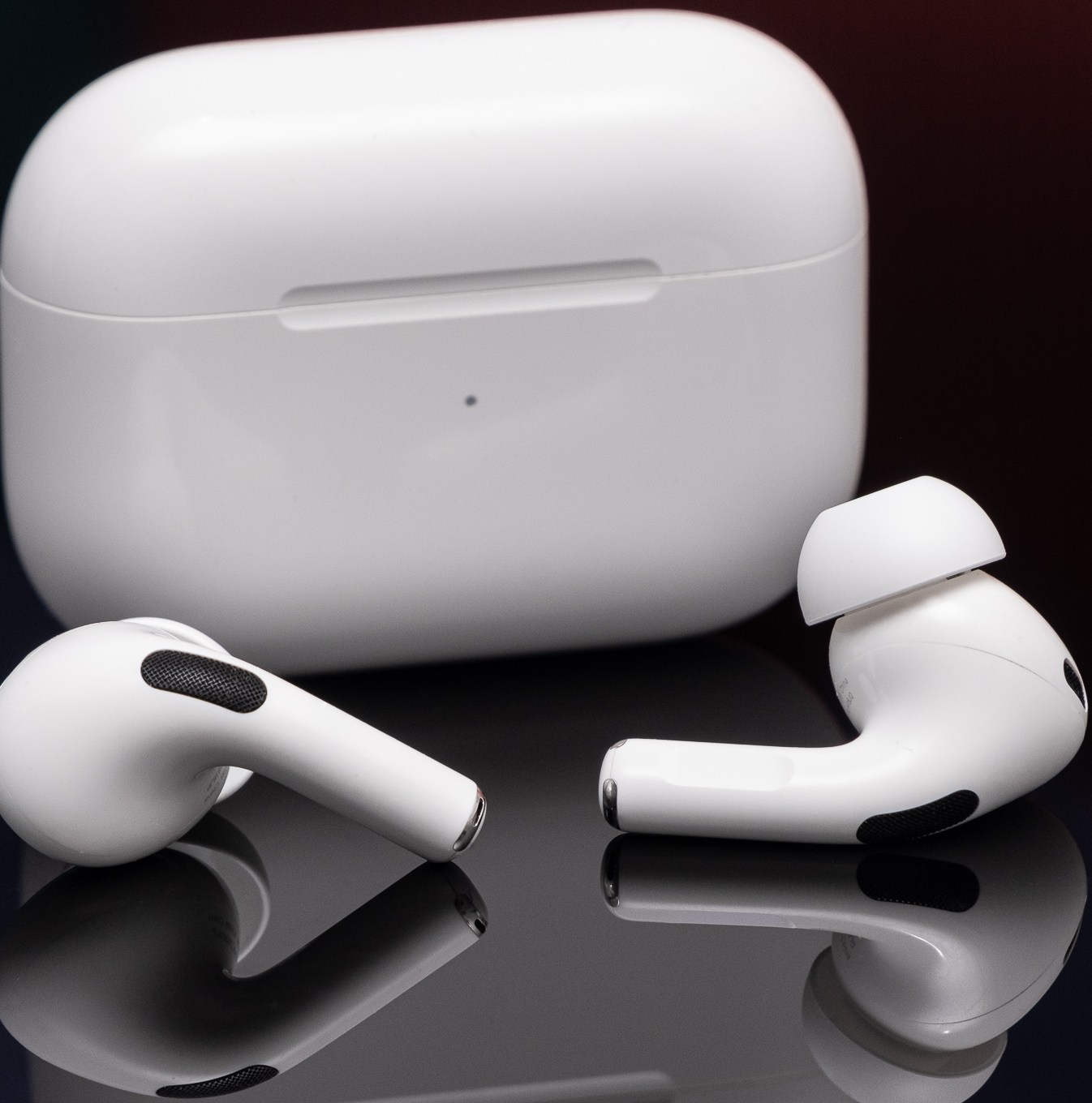 تم تصوير AirPods من الجيل الثاني من Apple على سطح أسود عاكس.